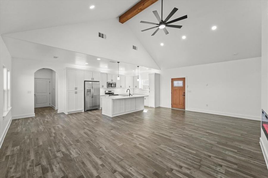 Unfurnished living room with beam ceiling, ceiling fan, high vaulted ceiling, and dark hardwood / wood-style flooring