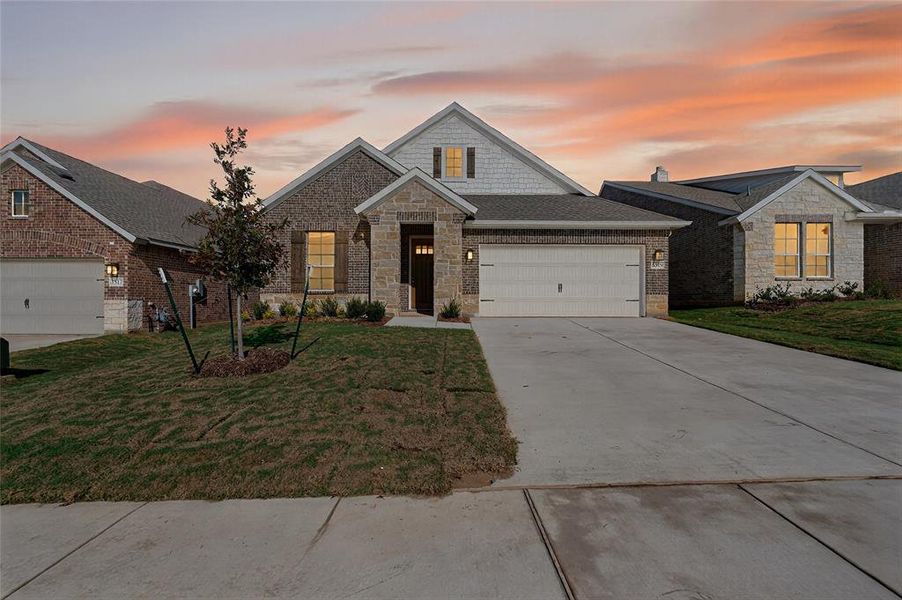 Craftsman inspired home featuring a front lawn, concrete driveway, an attached garage, a shingled roof, and brick siding