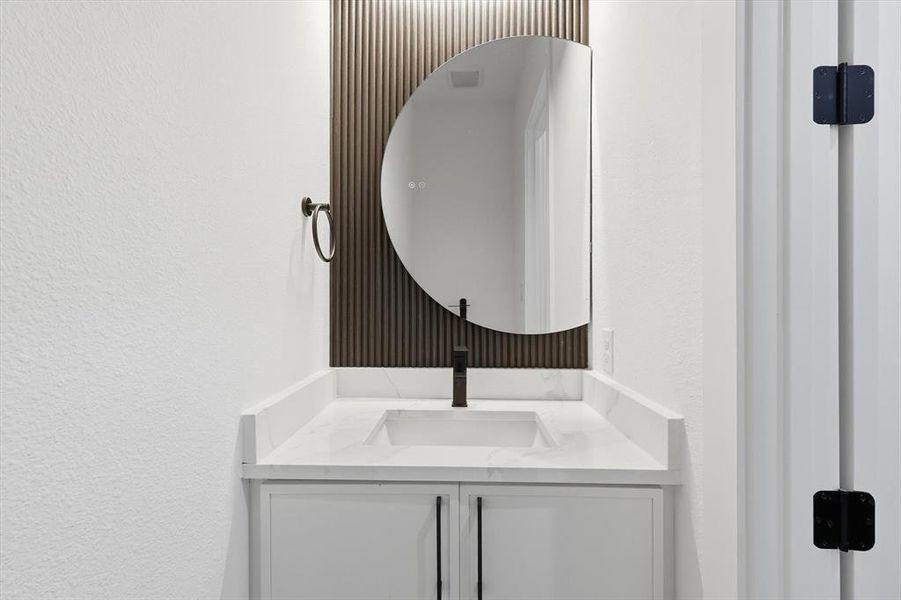 Bathroom featuring vanity and a textured wall Bathroom featuring vanity and a textured wall