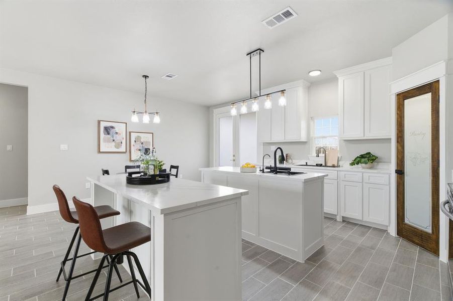 Kitchen featuring a breakfast bar area, pendant lighting, white cabinets, wood finish floors, and light stone counters