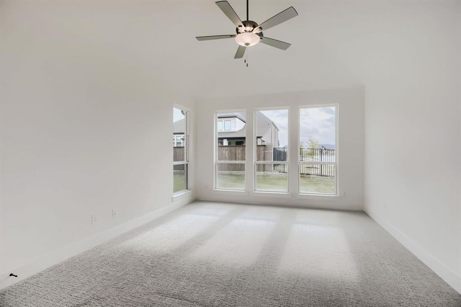 Spare room with carpet flooring, ceiling fan, and a high ceiling