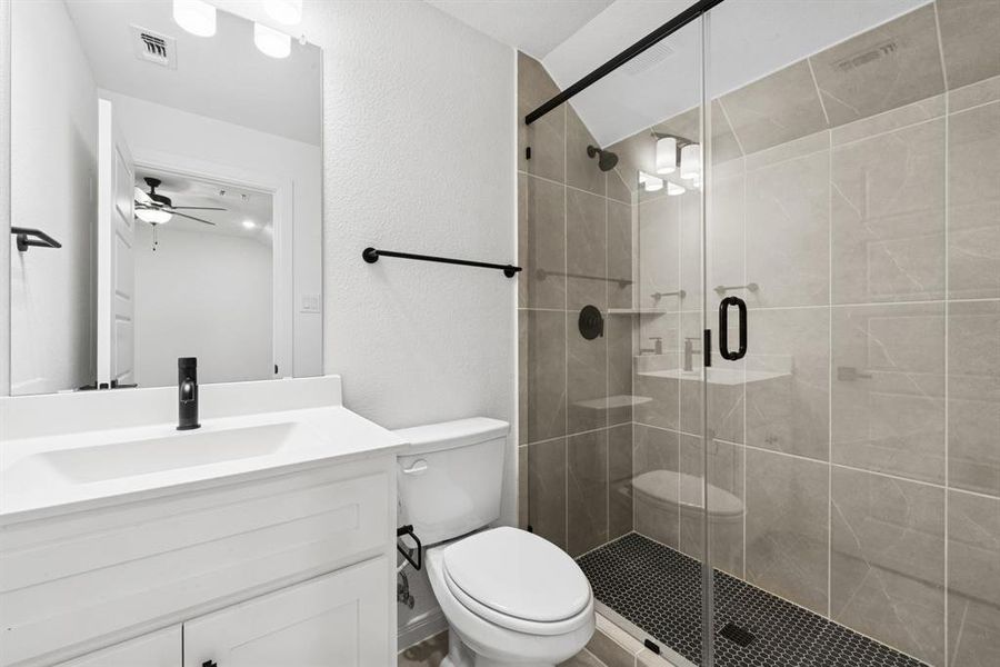 Bathroom with vanity, a shower stall, and a textured wall Bathroom with vanity, a shower stall, and a textured wall
