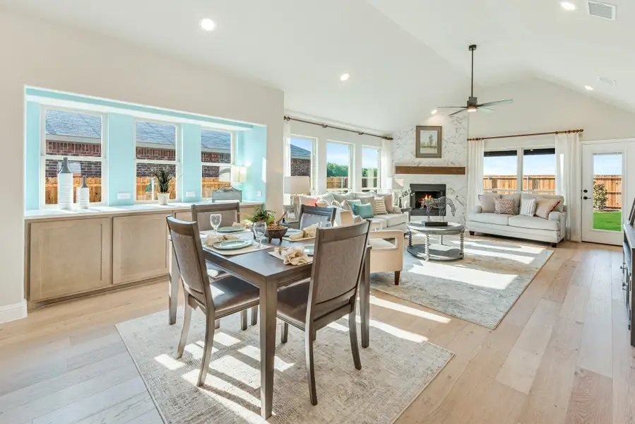 Open-concept dining and living area with vaulted ceiling, fireplace, and hardwood floors