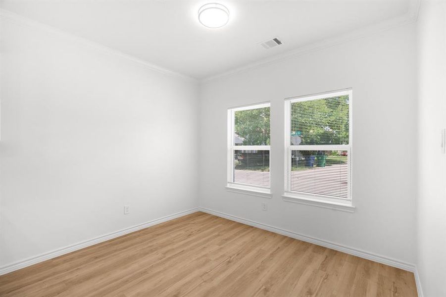 Unfurnished room featuring light wood-style flooring and crown molding Unfurnished room featuring light wood-style flooring and crown molding
