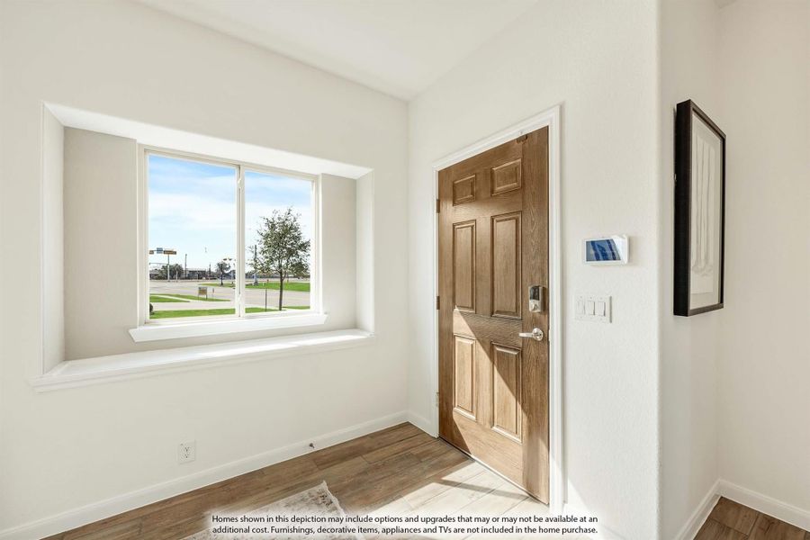 Entryway with wood front door, white walls, hardwood floors, and a window with outdoor view