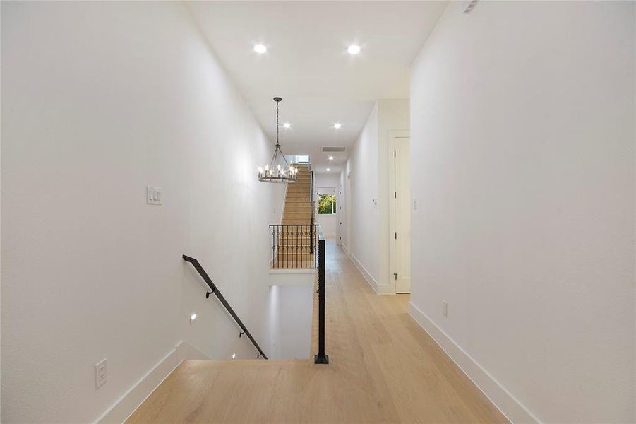 Corridor featuring an upstairs landing, recessed lighting, light wood-type flooring, and a chandelier