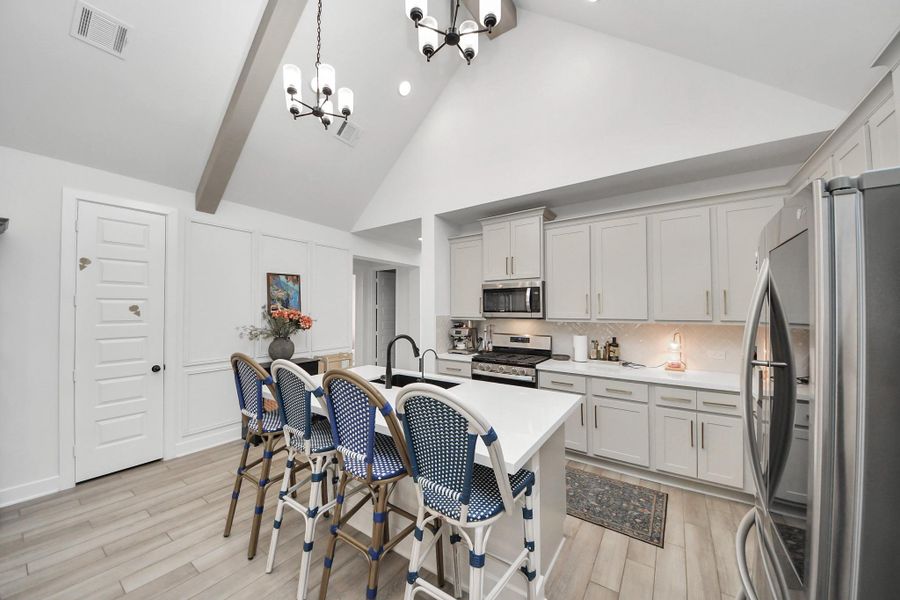 This modern kitchen features high vaulted ceilings, sleek white cabinetry, stainless steel appliances, and a central island with stylish blue and white barstools. The space is bright and inviting, perfect for cooking and entertaining. This modern kitchen features high vaulted ceilings, sleek white cabinetry, stainless steel appliances, and a central island with stylish blue and white barstools. The space is bright and inviting, perfect for cooking and entertaining.