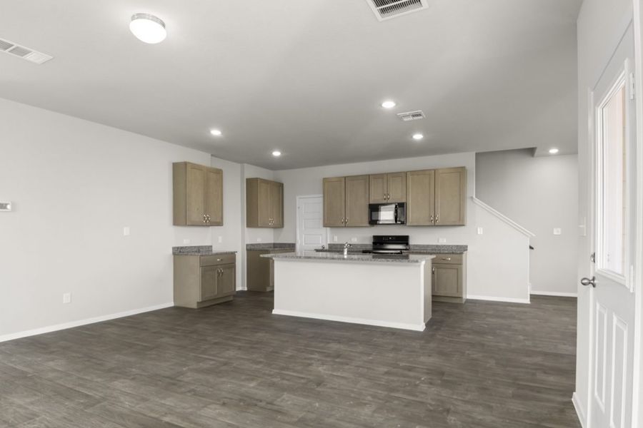 Image of a living room with grey walls, brown flooring, and a kitchen in the distance