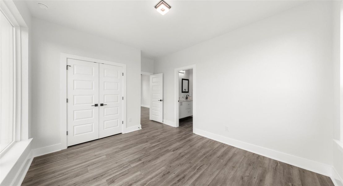 Unfurnished bedroom with a closet, wood finished floors, and ensuite bathroom
