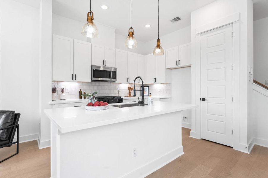 At the heart of this open-concept kitchen lies a stunning oversized island, offering generous prep space, sleek quartz countertops, and seating area. Whether you're hosting a dinner party or enjoying a casual breakfast, this island is the perfect gathering spot. Pendant lighting adds a touch of elegance, and the deep sink makes it as functional as it is beautiful.