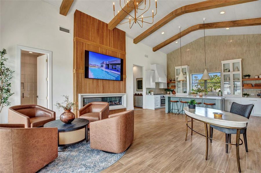 Living area with high vaulted ceiling, beamed ceiling, wood finish floors, a chandelier, and a glass covered fireplace Living area with high vaulted ceiling, beamed ceiling, wood finish floors, a chandelier, and a glass covered fireplace