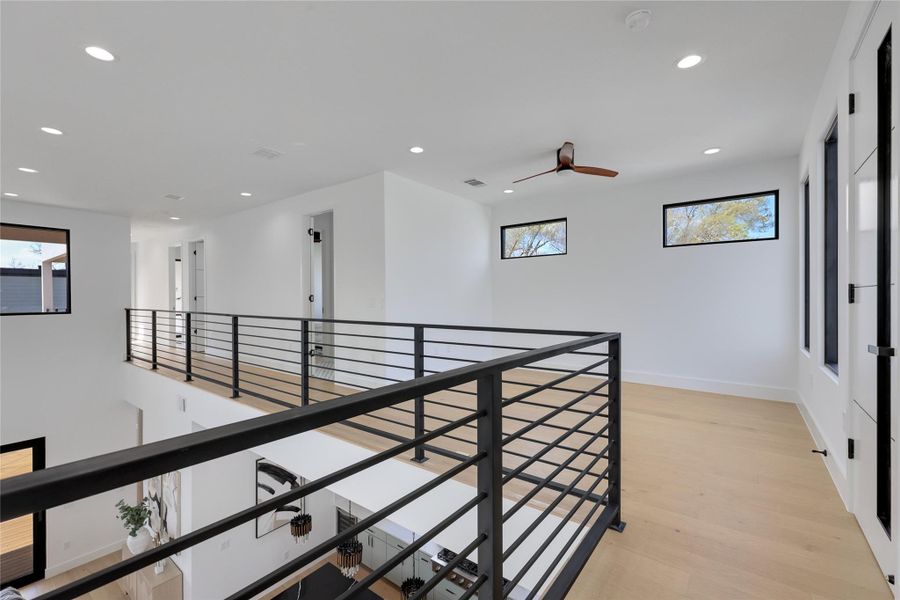 Hall featuring light wood finished floors, recessed lighting, and an upstairs landing