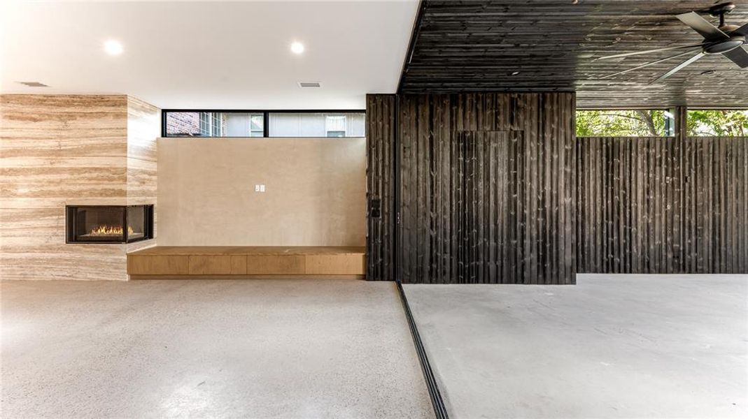 Living room with fireplace, opening to outdoor living area/patio with striking Shou Sugi Ban siding. Plenty of natural light.