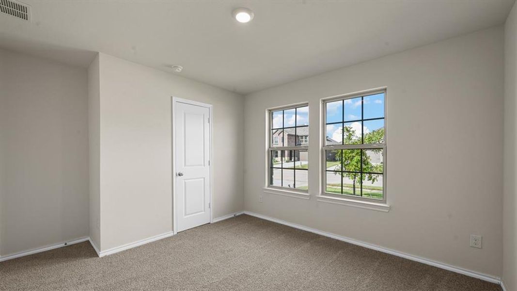 Neutral-toned room featuring two grid-pattern windows, light beige carpeting, white trim, a recessed ceiling light, and a white interior door with a brushed nickel knob Neutral-toned room featuring two grid-pattern windows, light beige carpeting, white trim, a recessed ceiling light, and a white interior door with a brushed nickel knob