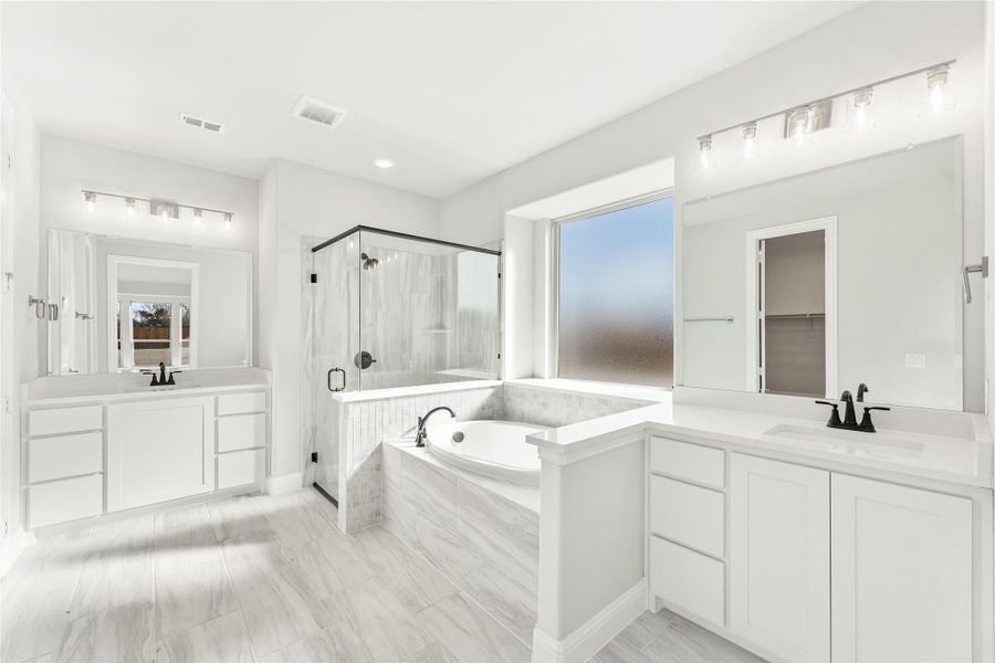 Master bathroom with dual vanities, soaking tub, glass shower, and white marble tile floors Master bathroom with dual vanities, soaking tub, glass shower, and white marble tile floors