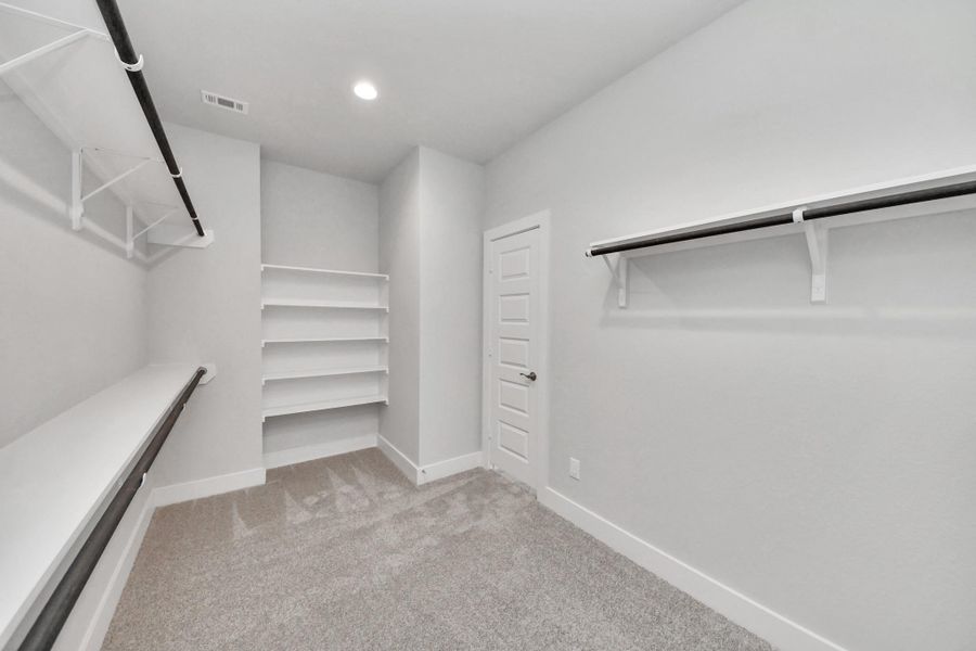 Walk-in closet that epitomizes luxury and practicality. This generously sized space features built-in shelving, offering abundant room for impeccable organization. High ceilings and recessed lighting create a bright and welcoming ambiance.