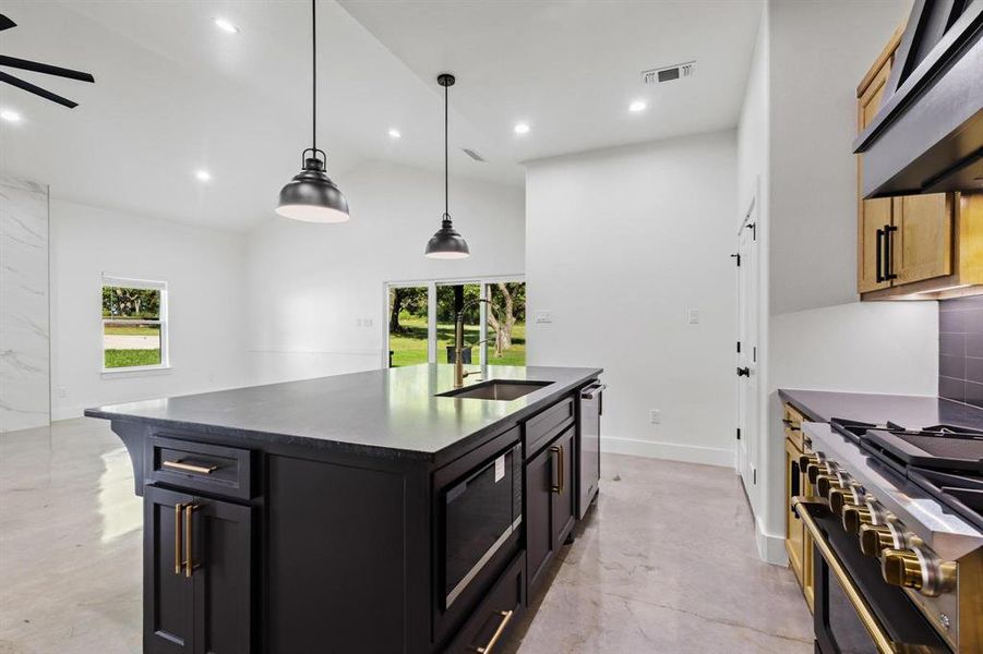 Kitchen featuring pendant lighting, appliances with stainless steel finishes, plenty of natural light, a kitchen island with sink, and recessed lighting