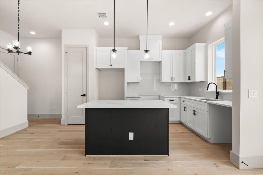 Full kitchen view — white shaker cabinetry, dark island, and open flow to dining Full kitchen view — white shaker cabinetry, dark island, and open flow to dining