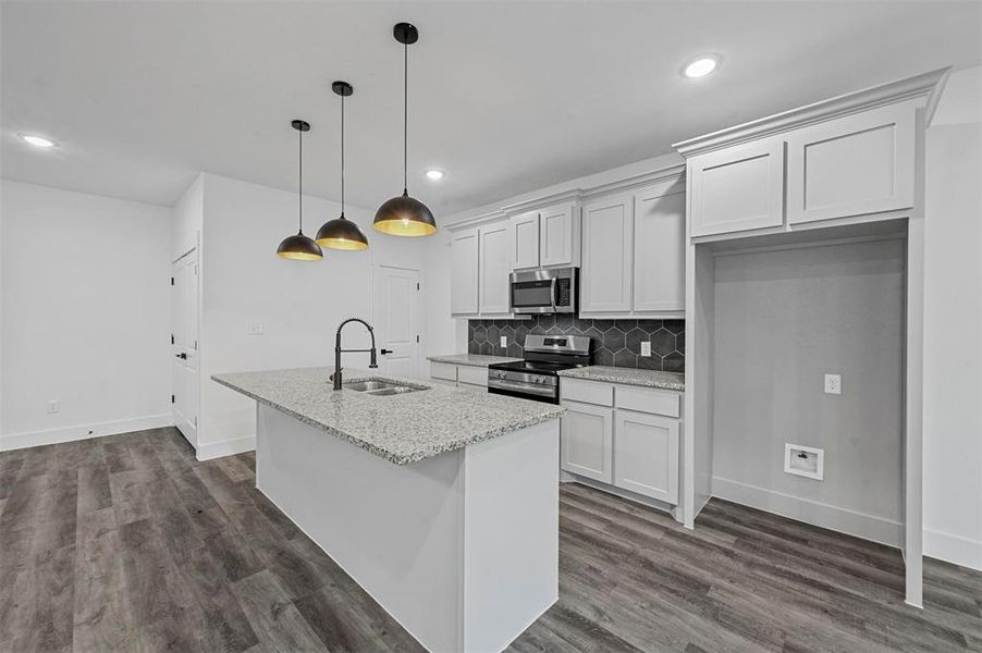 Kitchen featuring white cabinetry, dark hardwood / wood-style flooring, sink, light stone countertops, and appliances with stainless steel finishes