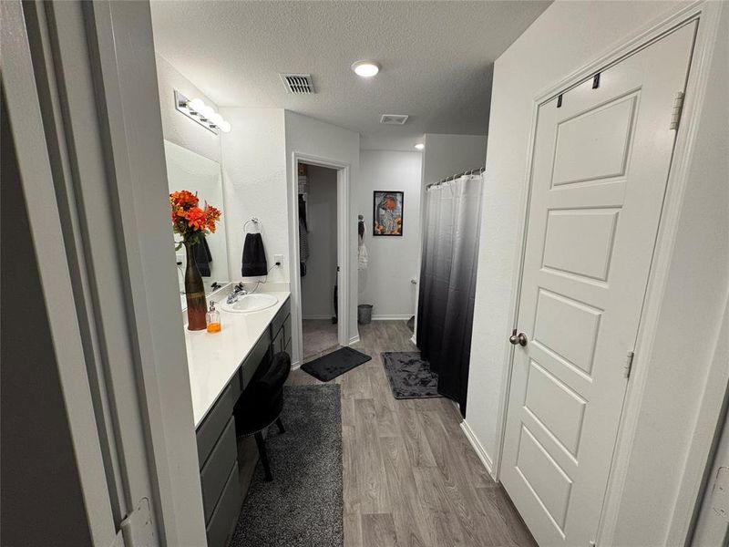 Bathroom with curtained shower, vanity, a textured ceiling, and hardwood / wood-style flooring