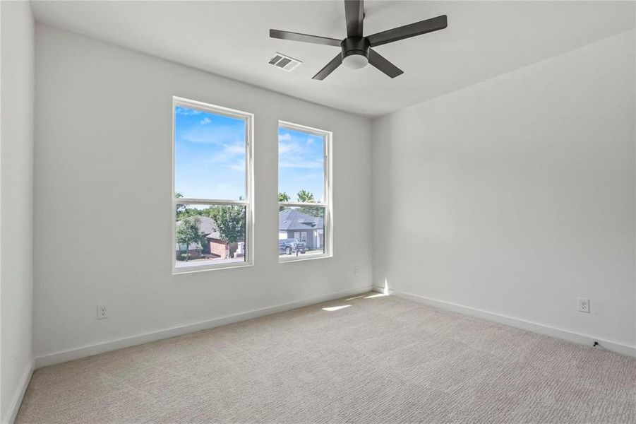 Empty room with light colored carpet and a ceiling fan Empty room with light colored carpet and a ceiling fan