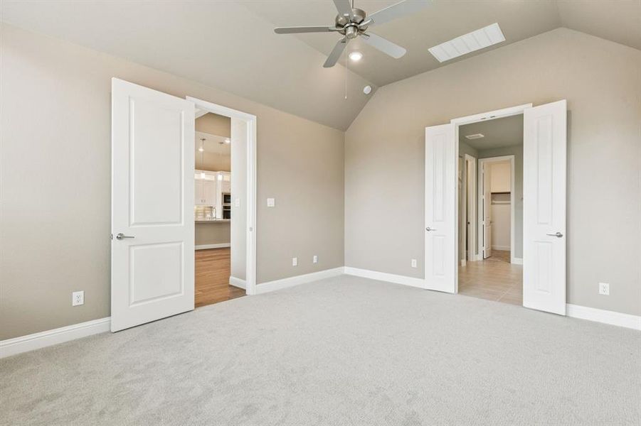 Unfurnished bedroom featuring carpet flooring, vaulted ceiling, and ceiling fan