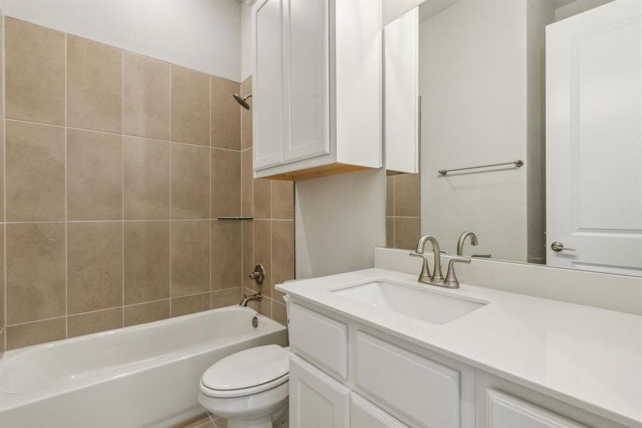 Full bathroom featuring vanity, toilet, and tiled shower / bath combo