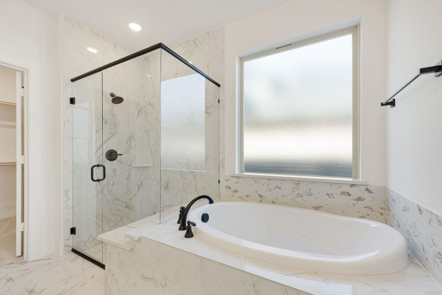 Master bathroom with soaking tub, glass-enclosed shower, and white marble tile throughout