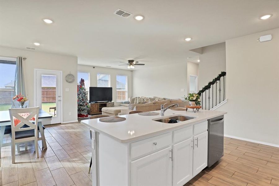 Kitchen with a wealth of natural light, dishwasher, sink, a kitchen island with sink, and white cabinets