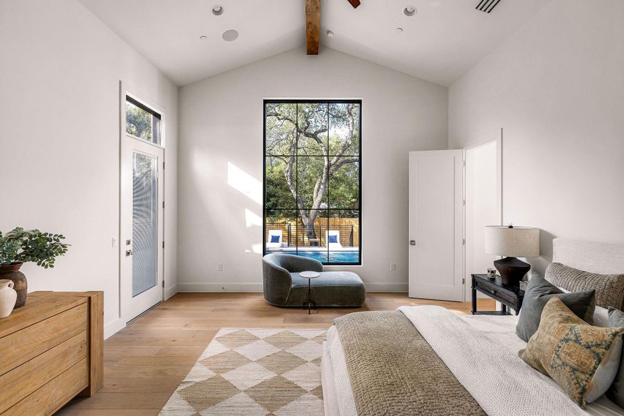 Natural light floods this spacious bedroom, highlighting its vaulted ceilings and rich wood flooring.
