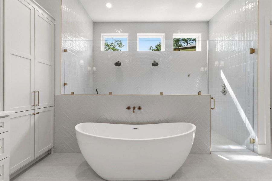 Stunning primary bath with Freestanding tub featuring wall-mounted faucet, frameless glass enclosure, dual shower heads, and herringbone tile design. Stunning primary bath with Freestanding tub featuring wall-mounted faucet, frameless glass enclosure, dual shower heads, and herringbone tile design.