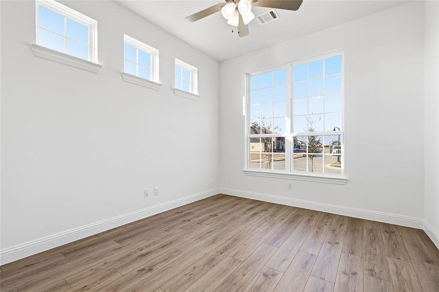 Empty room with ceiling fan and light wood-style flooring Empty room with ceiling fan and light wood-style flooring