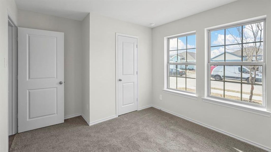 Unfurnished bedroom with light colored carpet and baseboards