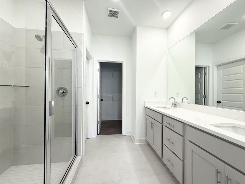 Bathroom featuring double vanity, a shower stall, and a spacious closet