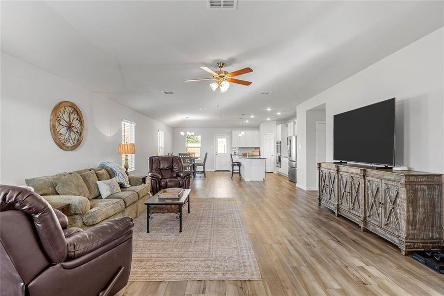 Living room with a chandelier, ceiling fan, light wood-type flooring, lofted ceiling, and recessed lighting
