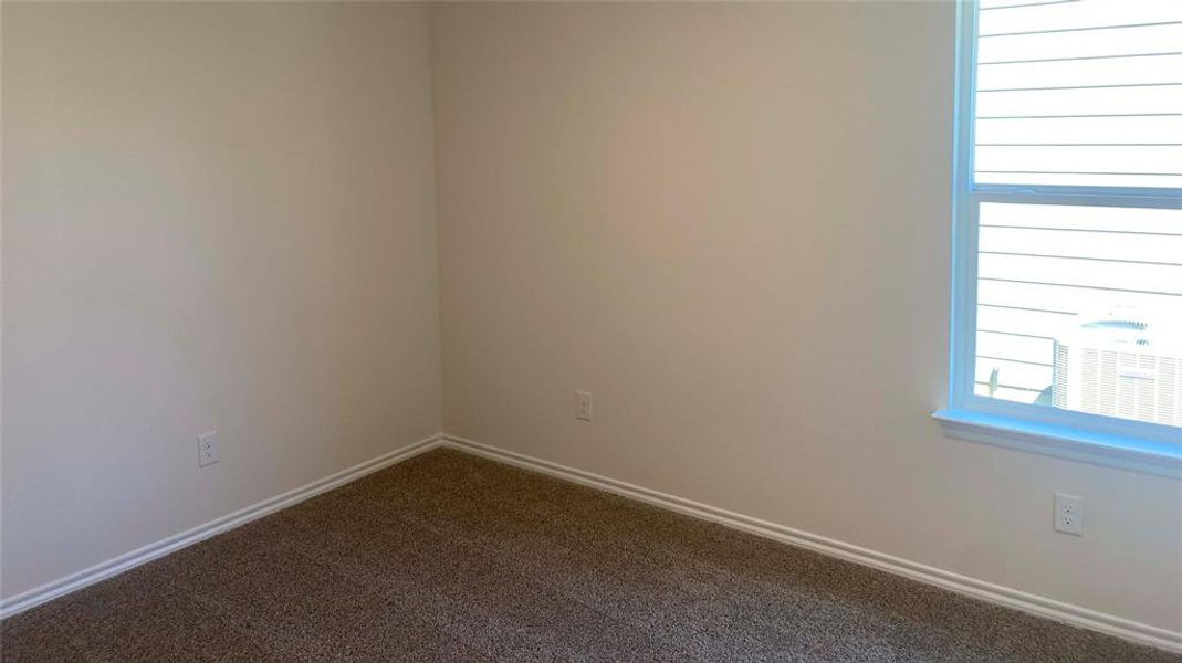 Empty room featuring baseboards and dark carpet