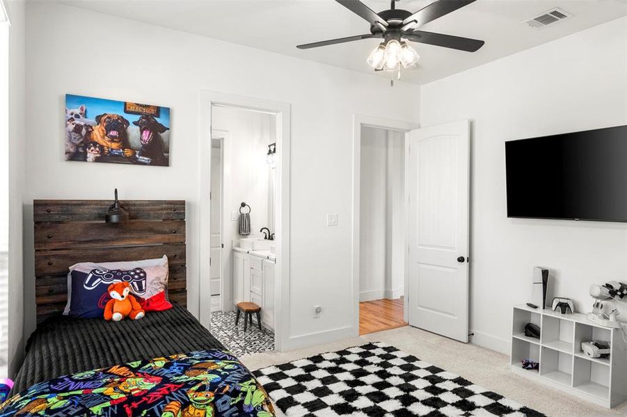 Bedroom with carpet, connected bathroom, large walk in closet and a ceiling fan