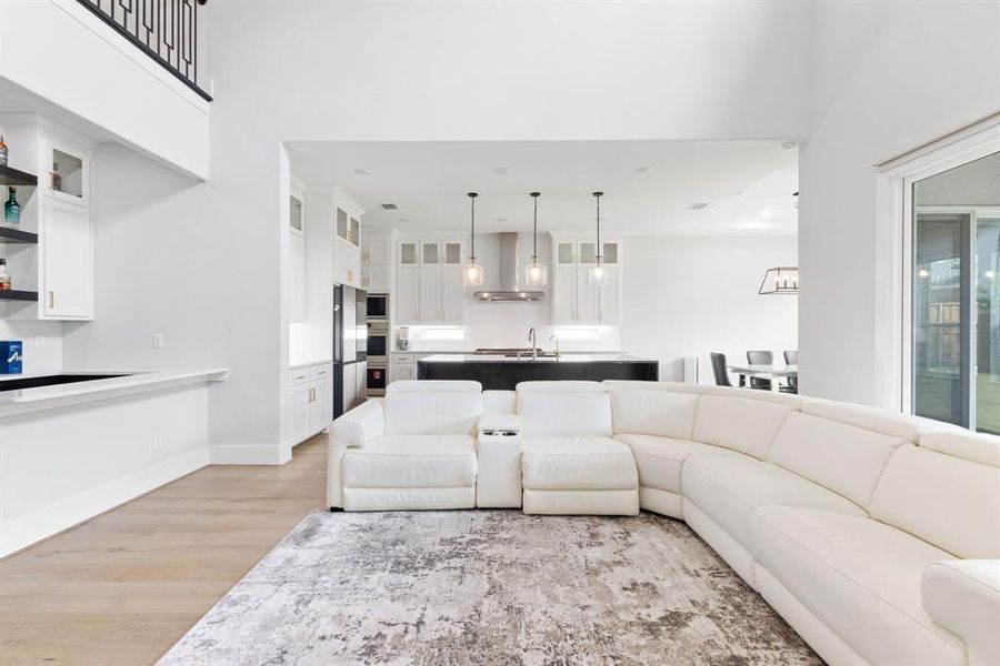 Living area with light wood-style floors, a high ceiling, and recessed lighting