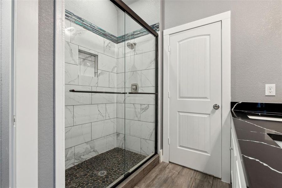 Bathroom with a shower with door, vanity, and hardwood / wood-style floors