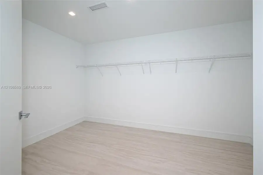 Walk-in closet featuring light wood-finish flooring, recessed lighting, and wall-mounted wire shelving