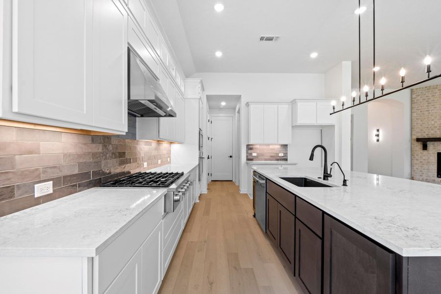 Kitchen featuring decorative backsplash, recessed lighting, light wood-style flooring, white cabinets, and a large island