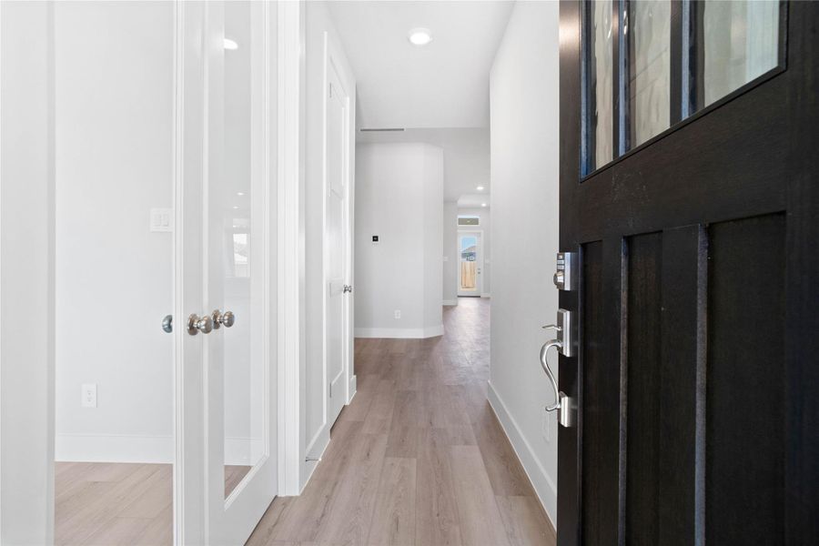 Welcome inside to a bright and inviting entryway that sets the tone for this modern home. Crisp white walls and abundant natural light create an open and spacious feel throughout the hallway. The luxury vinyl plank flooring extends seamlessly through the area, offering both aesthetic appeal and durability.