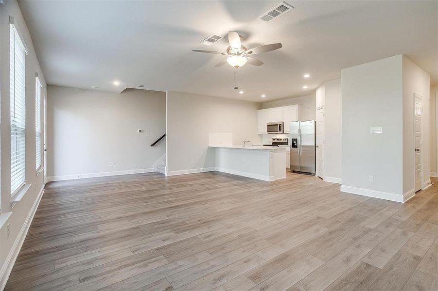 Unfurnished living room with stairway, recessed lighting, visible vents, and light wood-style floors