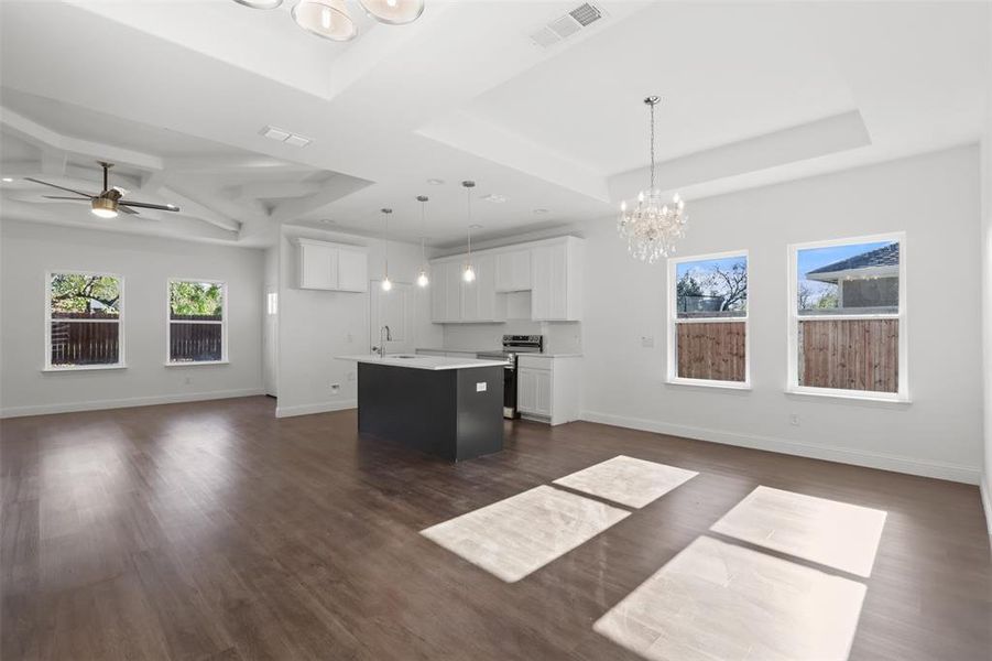 Kitchen with stainless steel range with electric cooktop, hanging light fixtures, an island with sink, dark hardwood / wood-style flooring, and white cabinetry