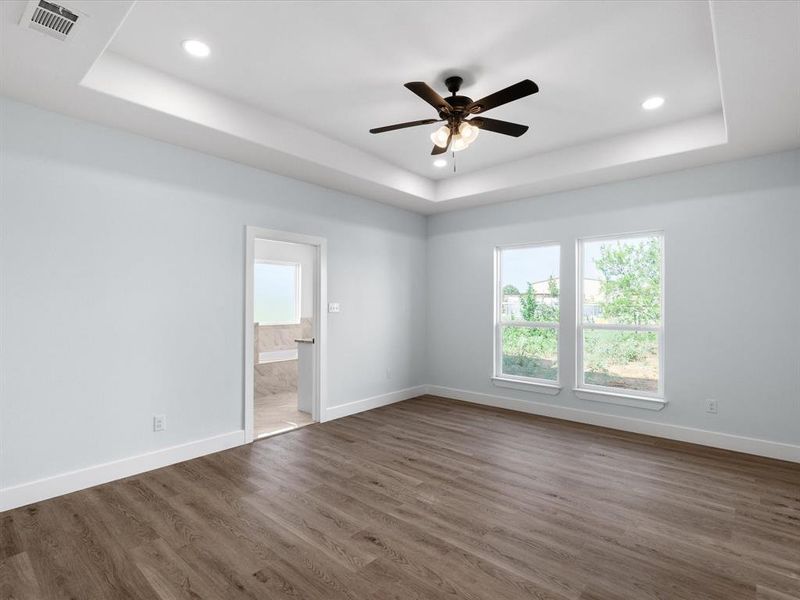 Spare room featuring plenty of natural light, a raised ceiling, recessed lighting, and dark wood finished floors