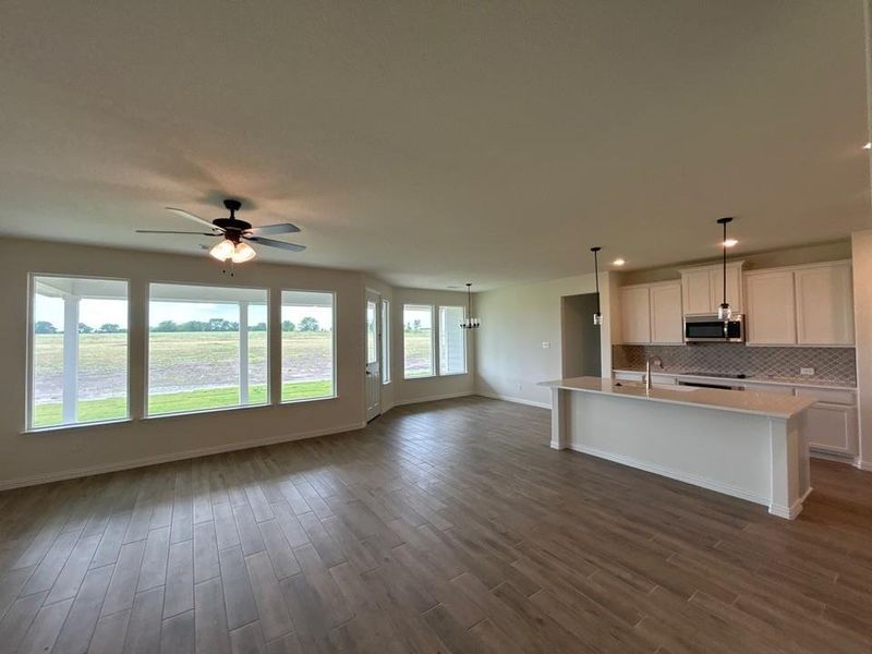 Open-concept living space featuring wood-finish flooring, a contemporary ceiling fan, and a wall of windows