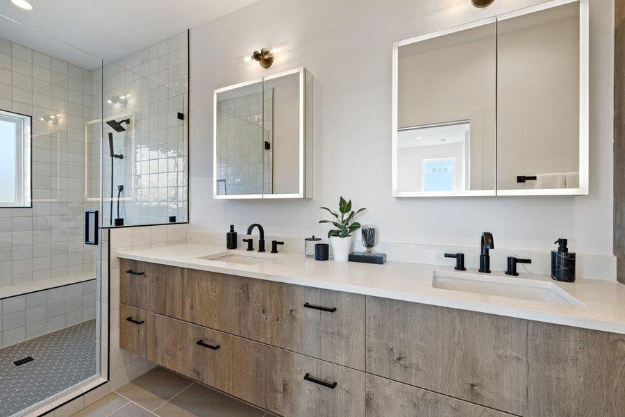 Full bath with double vanity, lighted medicine cabinet mirrors, large walk-in shower with bench, linen closet, and private toilet closet