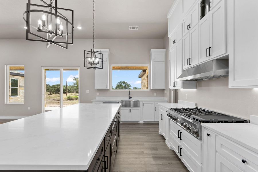 An inviting kitchen with a long center island, crisp white cabinetry, and modern light fixtures. An inviting kitchen with a long center island, crisp white cabinetry, and modern light fixtures.