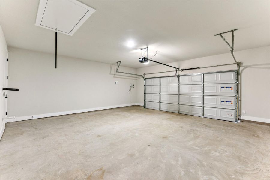 Garage featuring baseboards and a garage door opener Garage featuring baseboards and a garage door opener