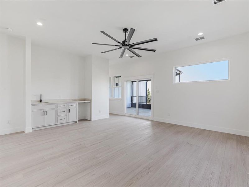Spacious game room featuring a bar area and direct access to a private balcony overlooking the backyard—perfect for entertaining or enjoying peaceful outdoor views.